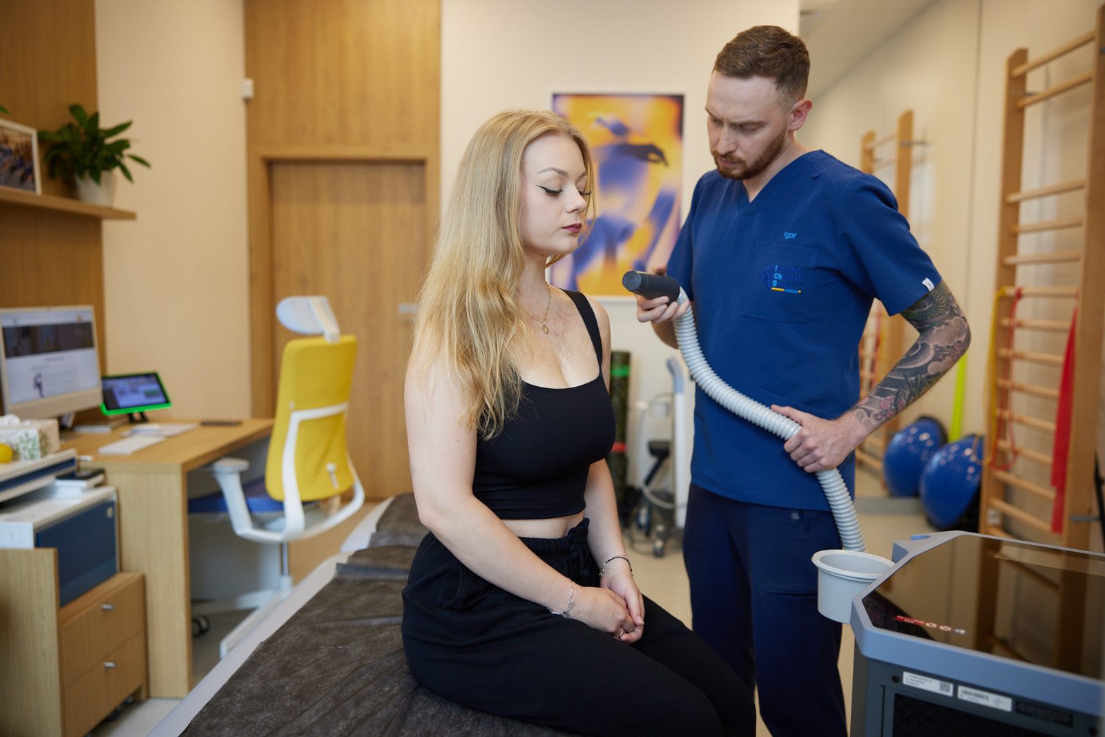 Fizjoterapeuta IChB wykonuje krioterapię miejscową barku siedzącej pacjentki